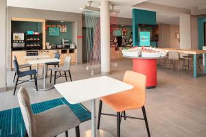 a cafeteria with tables and chairs and a kitchen at avid hotels - Madison - Monona by IHG in Monona