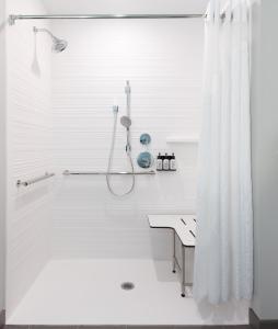 La salle de bains blanche est pourvue d'une douche et d'un lavabo. dans l'établissement avid hotels - Madison - Monona, an IHG Hotel, à Monona