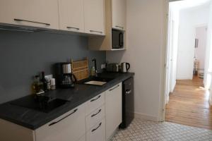 una cocina con encimera negra y armarios blancos en coeur de ville 2 pers, en Vannes