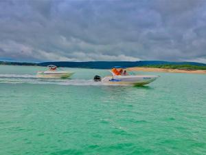 two speed boats in the water near a beach at Pousada Marina do Farol in São José da Barra