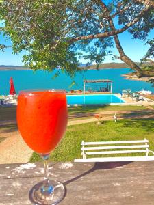 a drink sitting on a table next to the water at Pousada Marina do Farol in São José da Barra