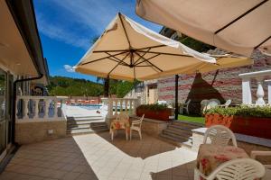 a largeige umbrella sitting on a patio with tables and chairs at Hotel Plaza in Tabiano