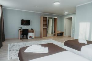 a large bedroom with two beds and a desk at Aral Hotel in Aralʼsk