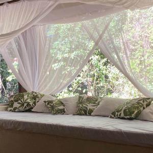 Cama con almohadas y dosel con ventana en Casa limão, en Trancoso