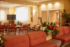 a waiting room with tables and chairs and a tv at Hotel Plaza in Tabiano
