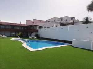 a swimming pool with green grass next to a building at Alojamiento vacacional Linaje del Pago in Sauzal