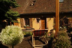 une chaise rouge assise sur une terrasse devant une maison dans l'établissement Gîte du Thalala, à Bernardvillé