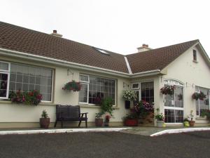 a white house with potted plants and a bench at The Yellow Rose B&B in Ballina