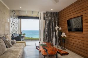 a living room with a couch and a television and the ocean at Sea front designer apartment in Ballito