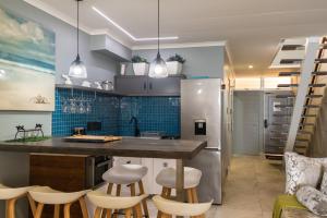 a kitchen with a counter and stools in a room at Sea front designer apartment in Ballito