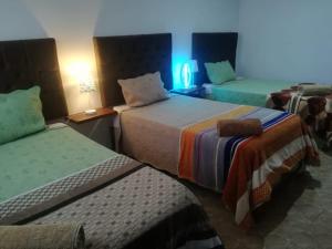 una camera d'albergo con due letti e una luce blu di Huacachina Desert House a Ica