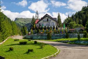 
a large house with a clock on the front of it at Piscul Negru Hotel - Transfagarasan in Cumpăna
