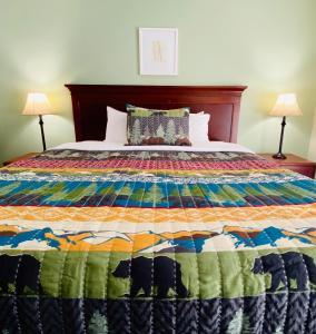 a bed with a colorful quilt on it with two lamps at Salida Inn & Monarch Suites in Salida