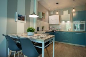 een keuken met blauwe kasten en een tafel en stoelen bij Apartament MOUNTSEA Pobierowo , Grunwaldzka in Pobierowo