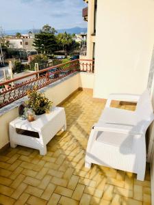 a balcony with two white chairs and a table at B&B Marilyn's House in Gragnano