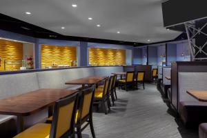 a restaurant with wooden tables and yellow chairs at Holiday Inn La Mirada Buena Park by IHG in La Mirada