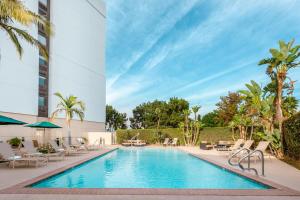 uma piscina num hotel com cadeiras e guarda-sóis em Holiday Inn La Mirada, an IHG Hotel em La Mirada