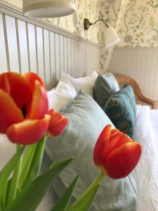 a bed with two red tulips next to a pillow at Villamilsten B&B in Lidköping