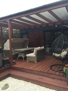 une terrasse en bois avec un canapé et une balançoire dans l'établissement Domek SunRelax z jacuzzi niedaleko Suntago, à Korytów