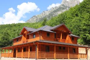 a large wooden house with mountains in the background at Bujtina Malaj in Valbonë