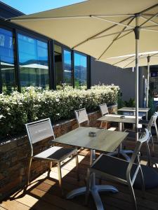 a patio with tables and chairs and an umbrella at Hotel Residence Lido Marana Bastia Furiani in Furiani
