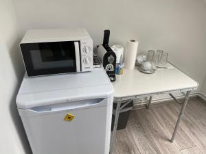 een magnetron bovenop een koelkast naast een tafel bij Ossiach Apartment 2 in Heiligen Gestade