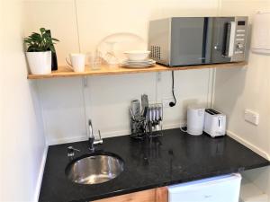 a kitchen counter with a sink and a microwave at The Hideout in Mangawhai