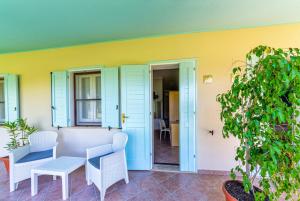 a patio with a table and chairs and a yellow wall at Agriturismo Is Cortillaris in Càbras