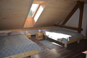 a attic bedroom with two beds and a window at Penzion Kota 509 in Janovice