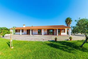 a house with a green lawn in front of it at Agriturismo Is Cortillaris in Càbras