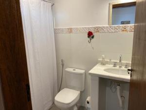 a white bathroom with a toilet and a sink at Pousada Fazenda Pinhalzinho in Ribeirão Claro
