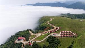 Flora Handüzü Resort Bungalow في ريزي: اطلالة جوية على جبل مع وجود الغيوم في الخلفية
