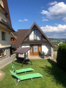 two lawn chairs and a table in front of a house at Domek u Bizioma in Murzasichle