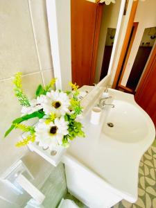 a bathroom with a sink with a vase of flowers at B&B Marilyn's House in Gragnano