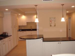 a kitchen with white cabinets and a black counter top at Island House Beach Resort 17S in Point O'Rocks