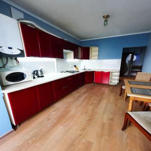 una cucina con armadi rossi e pavimenti in legno di Lux.Ap4you.if a Ivano-Frankivsʼk