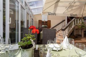 a table with glasses and a vase with a flower on it at Illés Hotel in Szeged