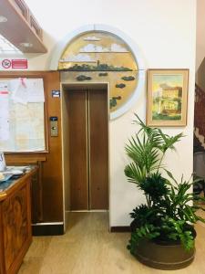 einem Bürokorridor mit Tür und Topfpflanze in der Unterkunft Hotel Milano in Grado