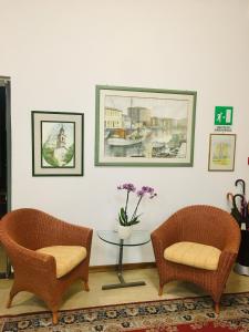 uma sala de estar com duas cadeiras e uma mesa com flores em Hotel Milano em Grado