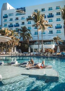 um grupo de pessoas sentadas na piscina de um hotel em Hard Rock Hotel Vallarta All Inclusive em Nuevo Vallarta