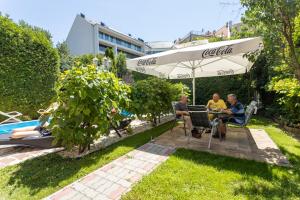 a group of people sitting at a table under an umbrella at Illés Hotel in Szeged