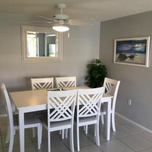 une salle à manger avec une table et des chaises blanches dans l'établissement Island House Beach Resort 13, à Point O'Rocks