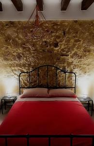 een rood bed in een kamer met een stenen muur bij Il Ronco di Archimede in Siracusa