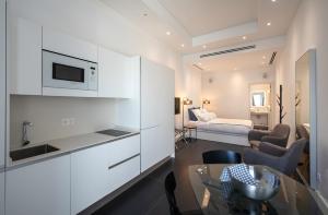a kitchen with white cabinets and a living room with a bed at VIVIENDAS VACACIONALES EL MANGO in Santa Cruz de la Palma