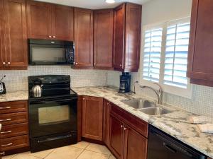 a kitchen with wooden cabinets and a stove and sink at Island House Beach Resort 28 in Point O'Rocks