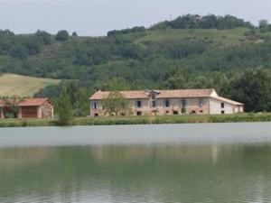 a house sitting next to a large body of water at La Ferme O Délices in Mazères