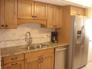 a kitchen with wooden cabinets and a stainless steel refrigerator at Island House Beach Resort 12N in Point O'Rocks