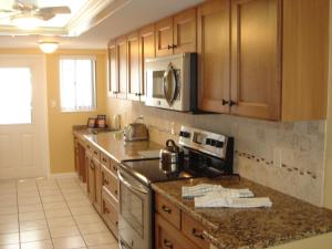 a kitchen with wooden cabinets and stainless steel appliances at Island House Beach Resort 12N in Point O'Rocks