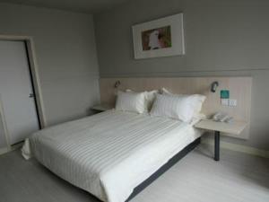1 dormitorio con 1 cama blanca grande y teléfono en Jinjiang Inn Bazhou High Speed Railway Station Yijin South Road Branch, en Langfang