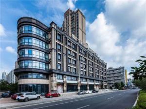 a large building with cars parked on the side of a street at JinJiang InnSelect Suzhou Shengze Shunhuxilu Hotel in Suzhou